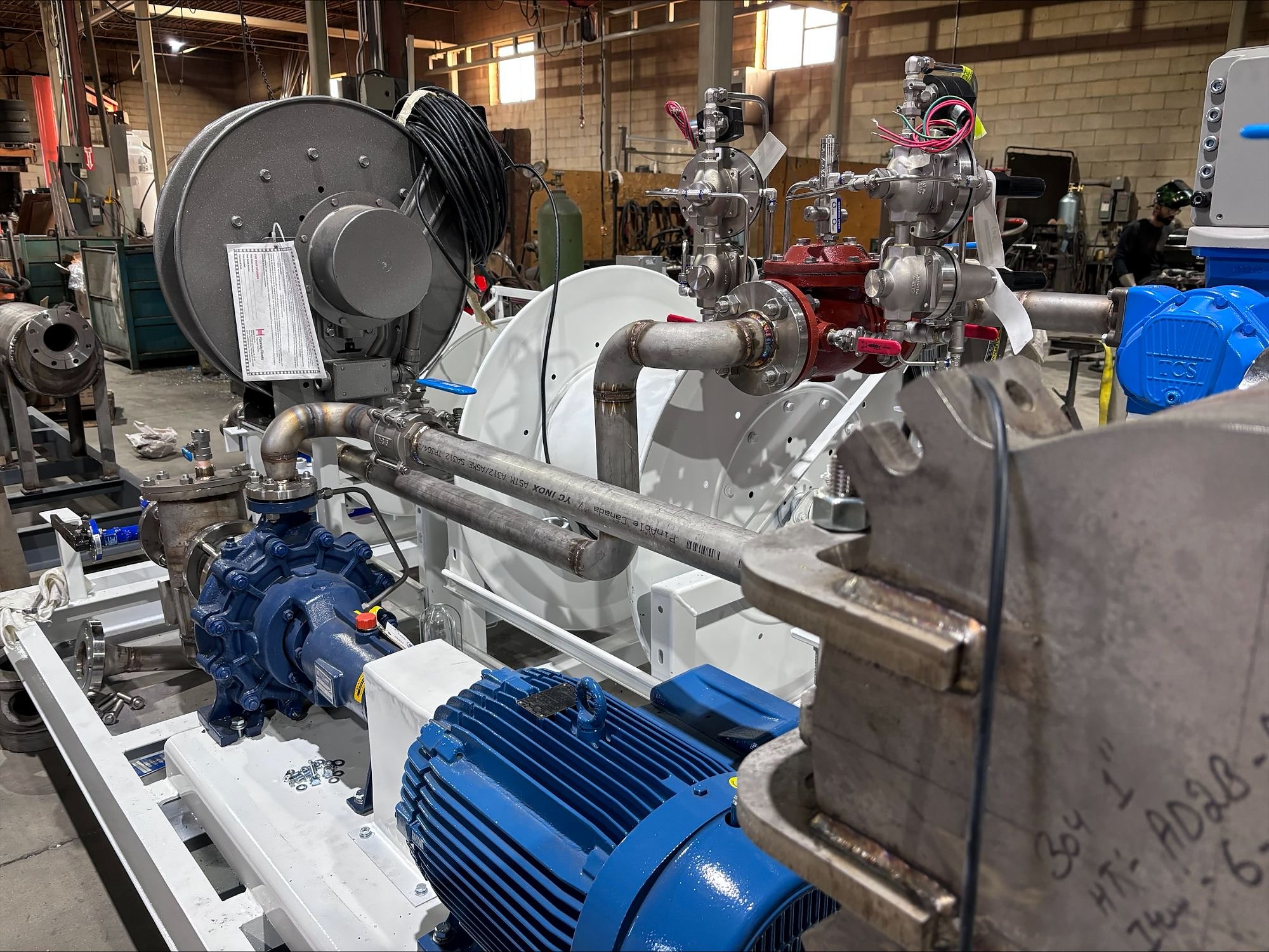 Pump skid in fabrication with electric pump, control valve, meter and hose reels