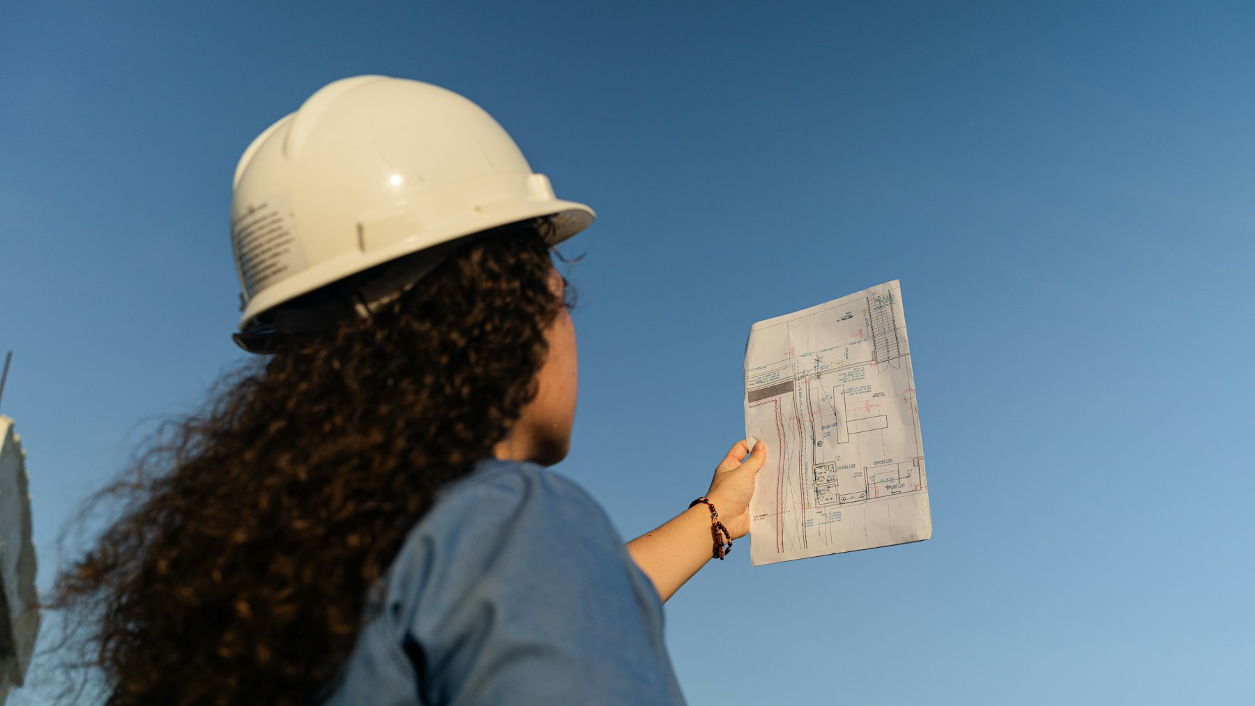Engineer in a hard hat reviewing project drawings on site